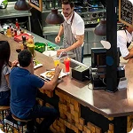barra restaurante con garzon y personas comiendo