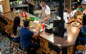 barra restaurante con garzon y personas comiendo